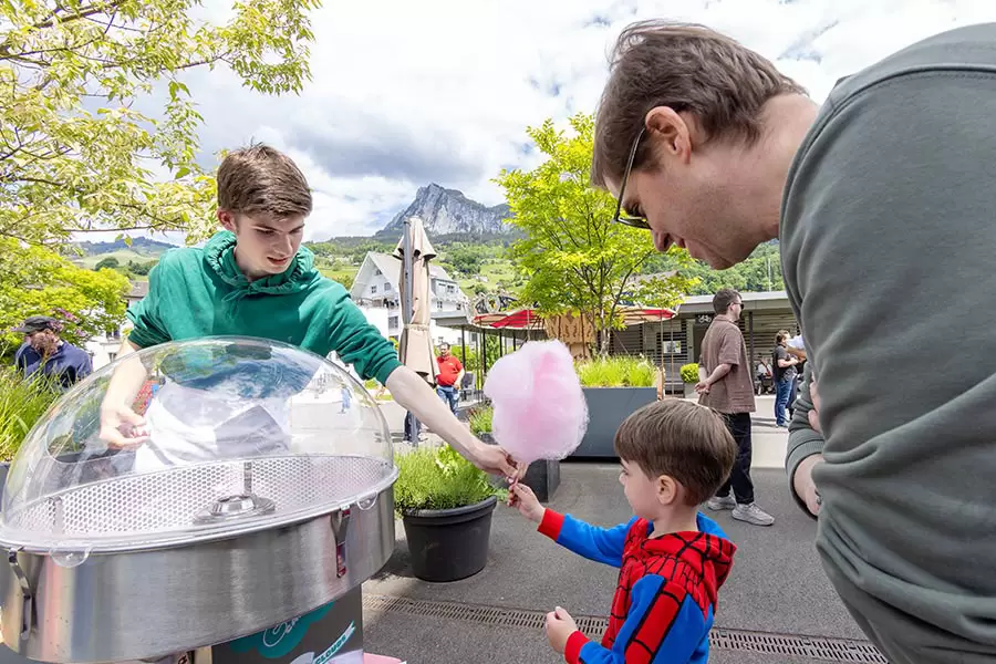 Zuckerguss! – Ein Schüler der Privatschule Hofstatt Schwyz beglückt einen jungen Festbesucher mit frischer, selbst gedrehter Zuckerwatte.