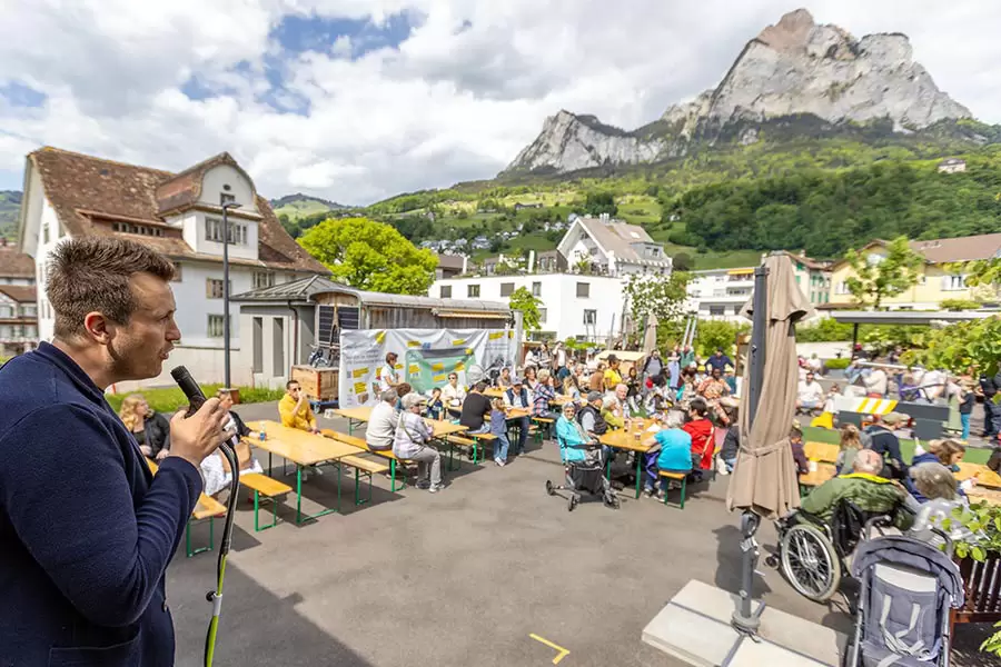 Hoi zäme! – Silas Inderbitzin, Leiter der Privatschule Hofstatt Schwyz (im Hintergrund das Schulhaus im historischen Haus Acher) und Fest-Mitorganisator, begrüsst die Festgemeinde.